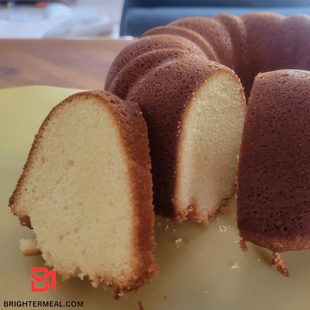 A tantalizing golden-brown Country Pound Cake, adorned with a dusting of powdered sugar, showcases its rich texture and moist crumb. The cake sits atop a vintage cake stand, exuding a delightful aroma that invites you to savor the timeless flavors of this classic dessert. The simplicity of its appearance belies the intricate layers of taste waiting to be discovered within each slice. A visual feast for the senses, the Country Pound Cake epitomizes the perfect blend of tradition and culinary artistry.
