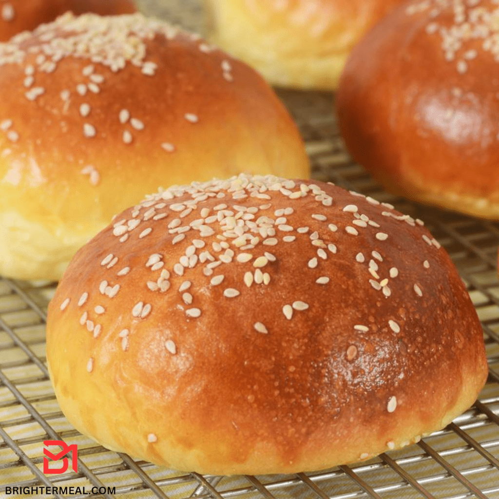 A batch of freshly baked soft bread rolls on a cooling rack.