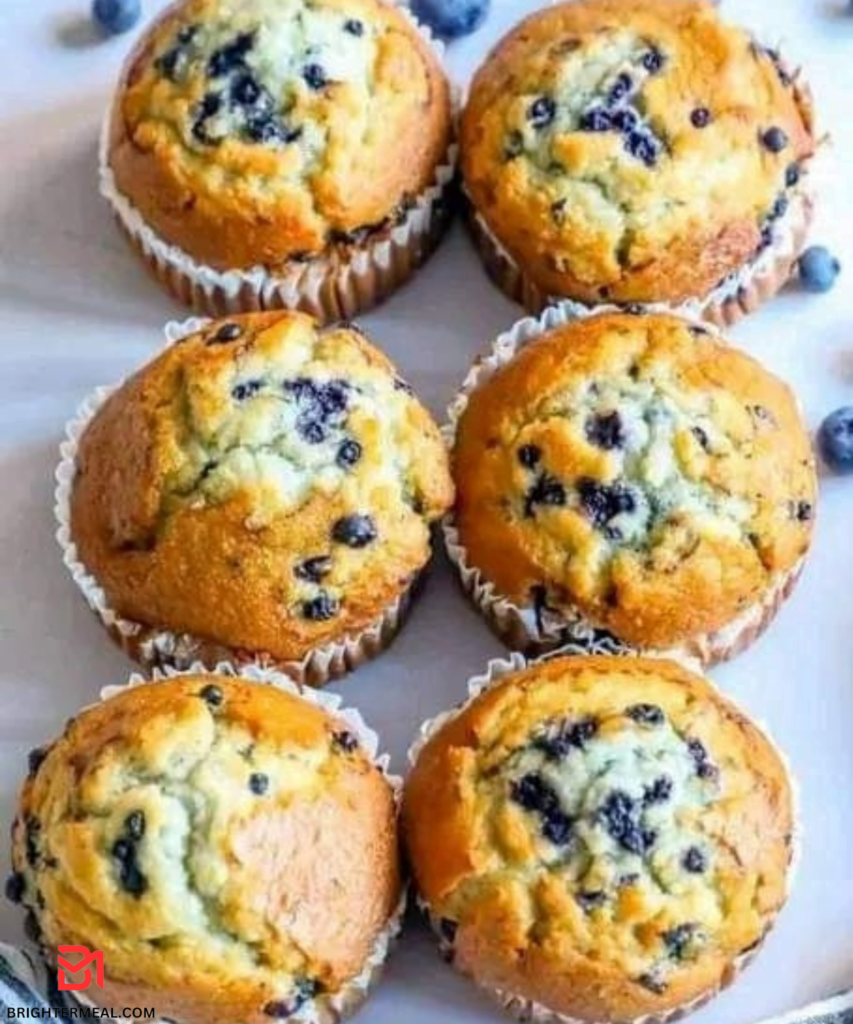 A close-up image of freshly baked triple berry muffins topped with a dusting of powdered sugar