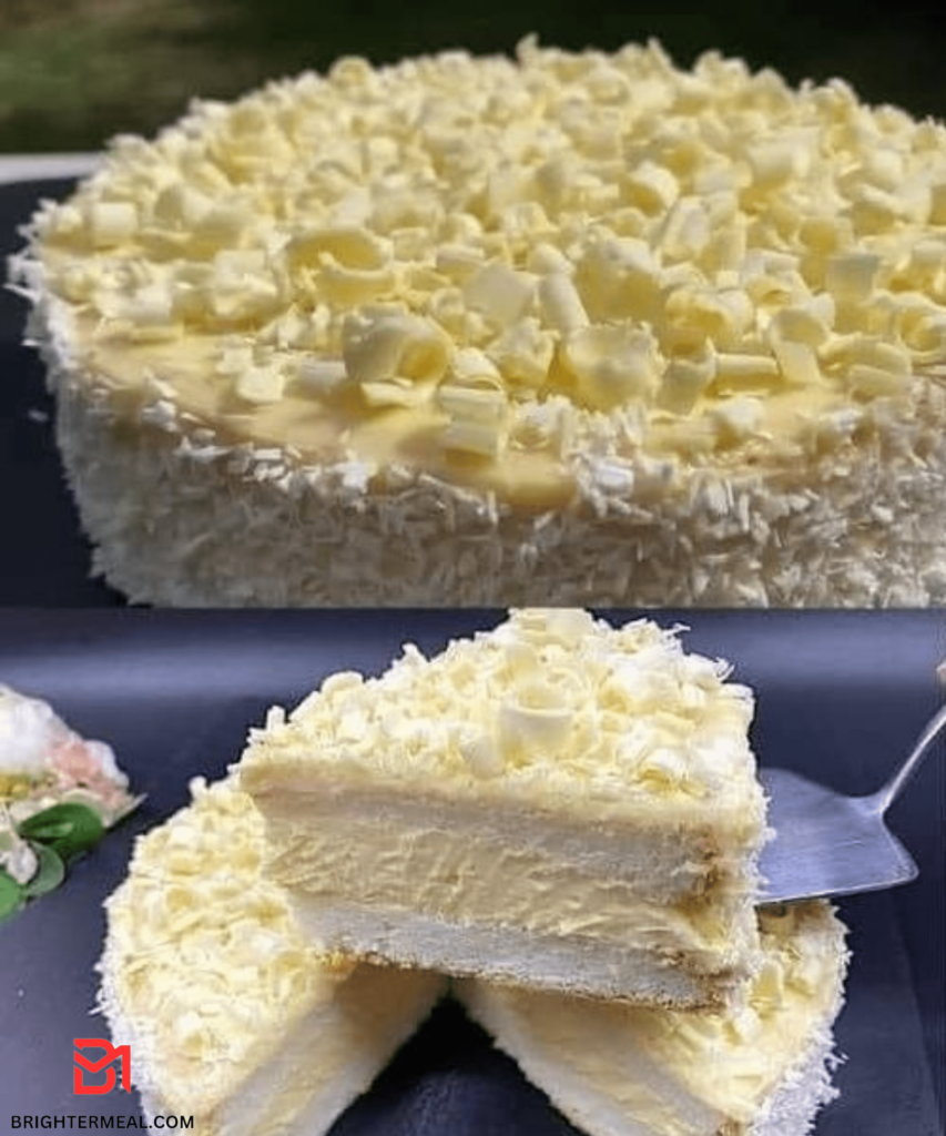 A close-up image of a slice of Coconut White Chocolate Cake topped with shredded coconut and white chocolate chips